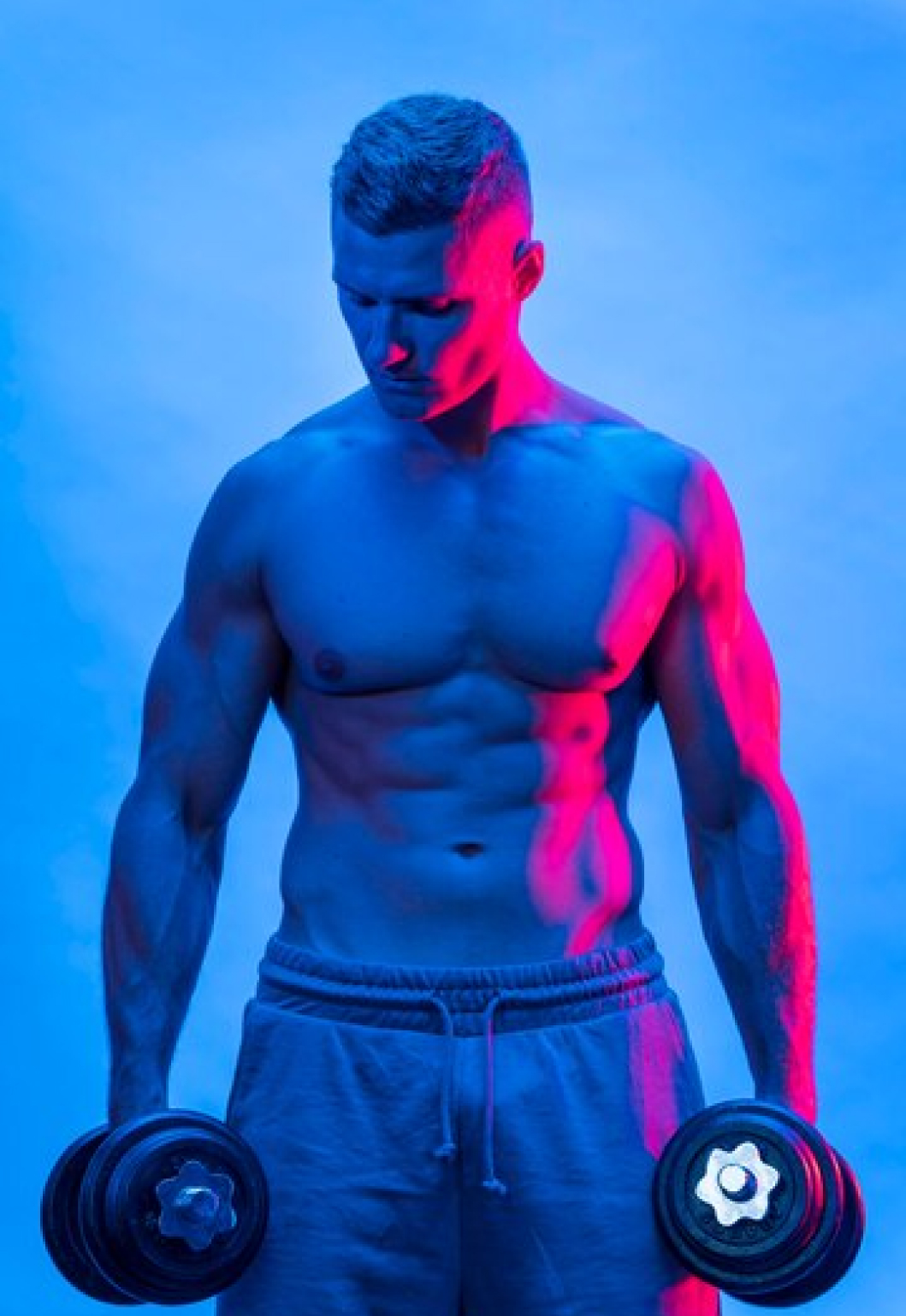 Мускулистый мужчина с гантелями в руках